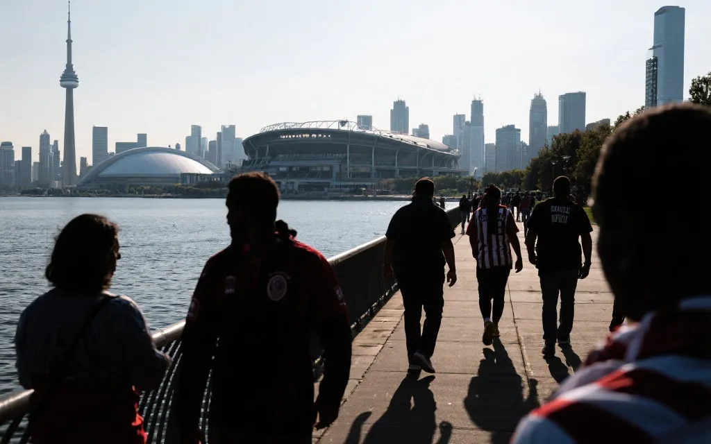 多伦多湖滨步道与球场比赛日氛围，球迷人群剪影，城市天际线，纪实摄影风格